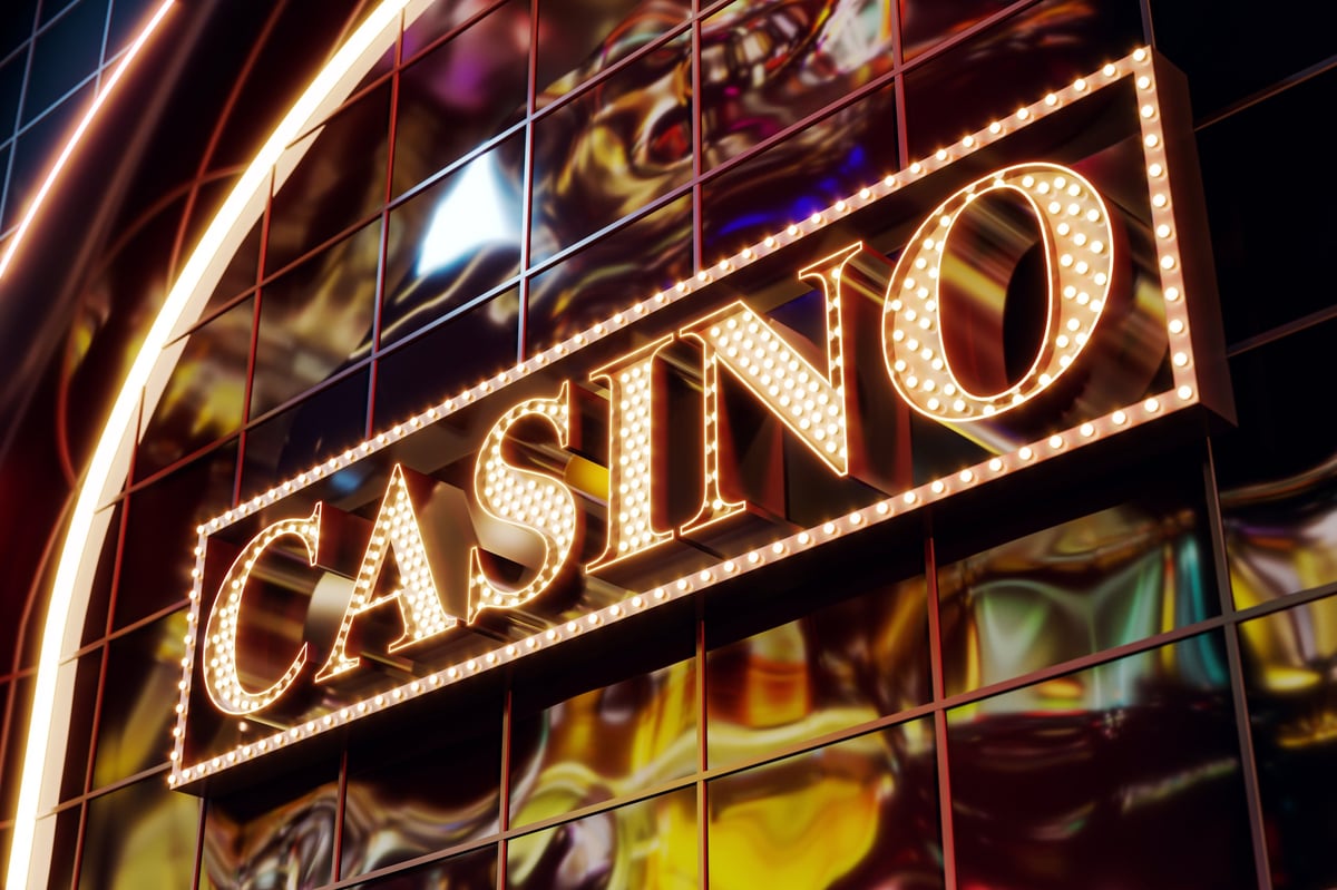 Illuminated vintage casino signage with glowing lights on reflective modern building facade at night