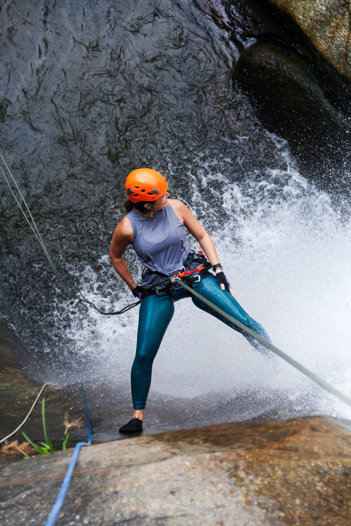 Adventurer rappelling down waterfall in tropical forest