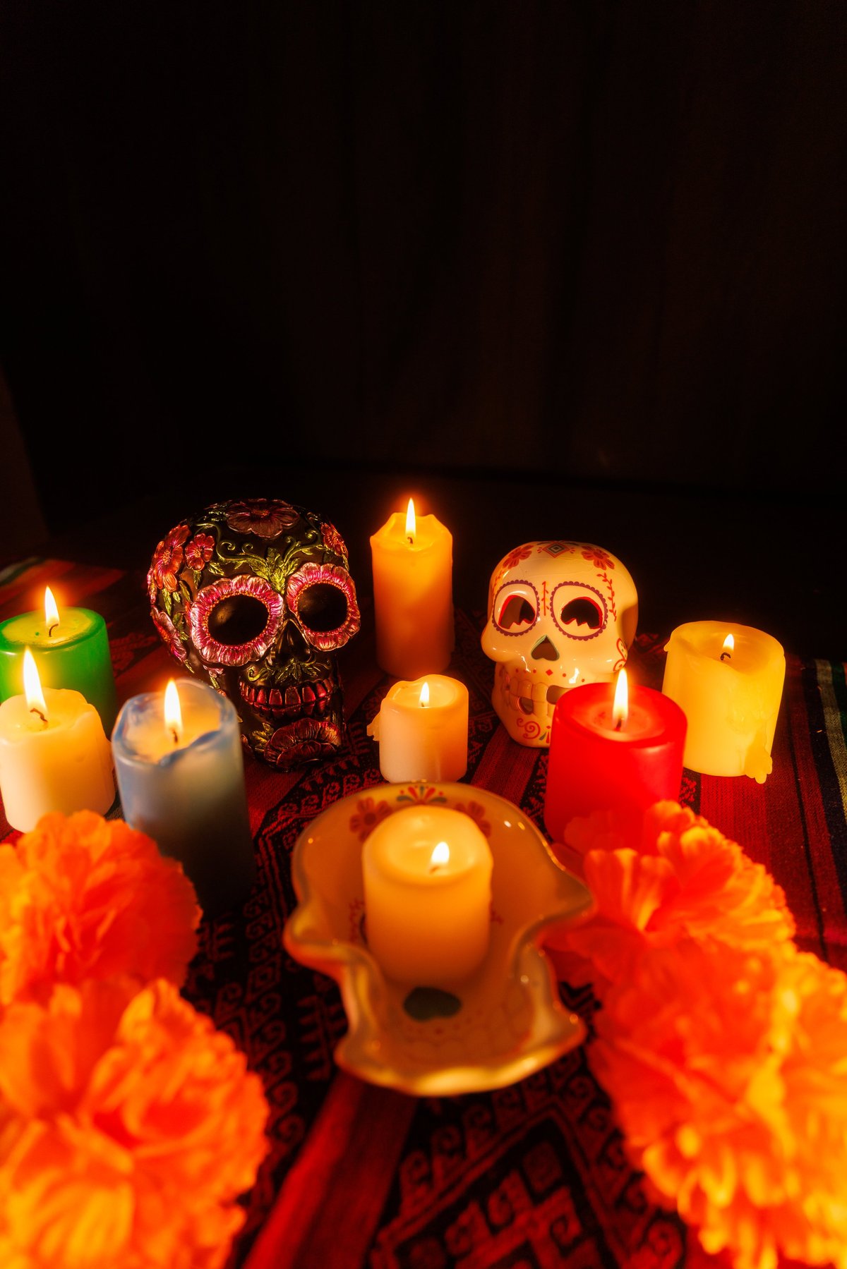 Colorful setup with skulls and candles surrounded by magnolia flowers reflects a heartfelt Day of the Dead tradition.