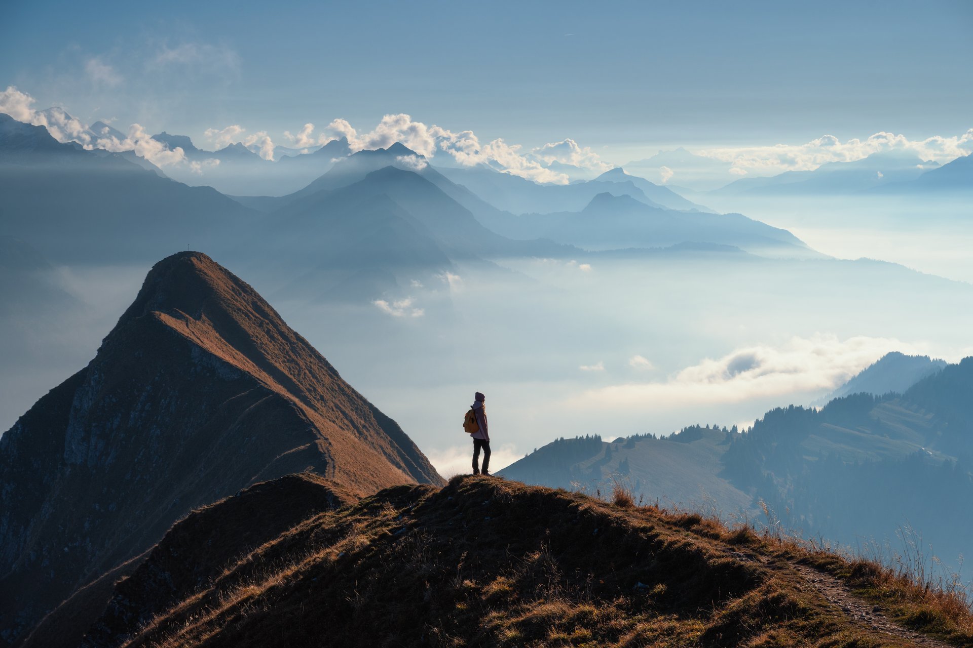 Mujer con mochila de pie en una cresta de montaña sobre las nubes