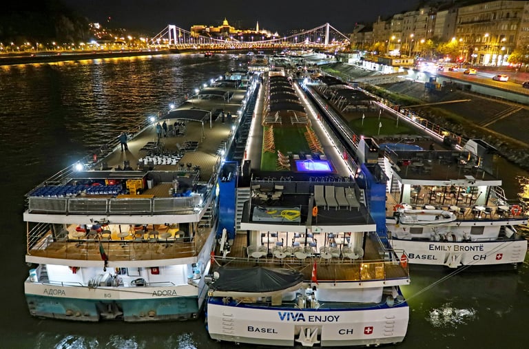 Budapest, Hungary. Illuminated cruise ships moored on the river Danube at night. Wet autumn night outdoors.
