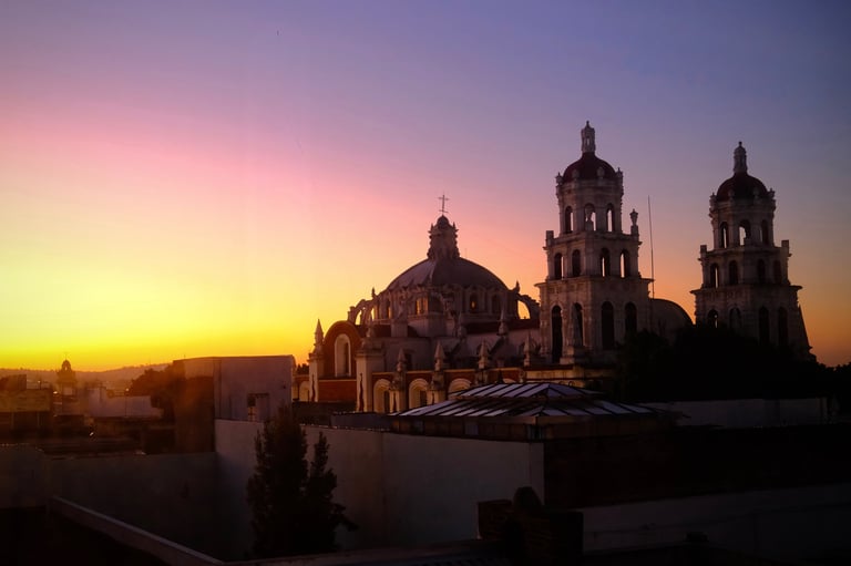 A cathedral silhouette stands against a glowing sunset sky over the city