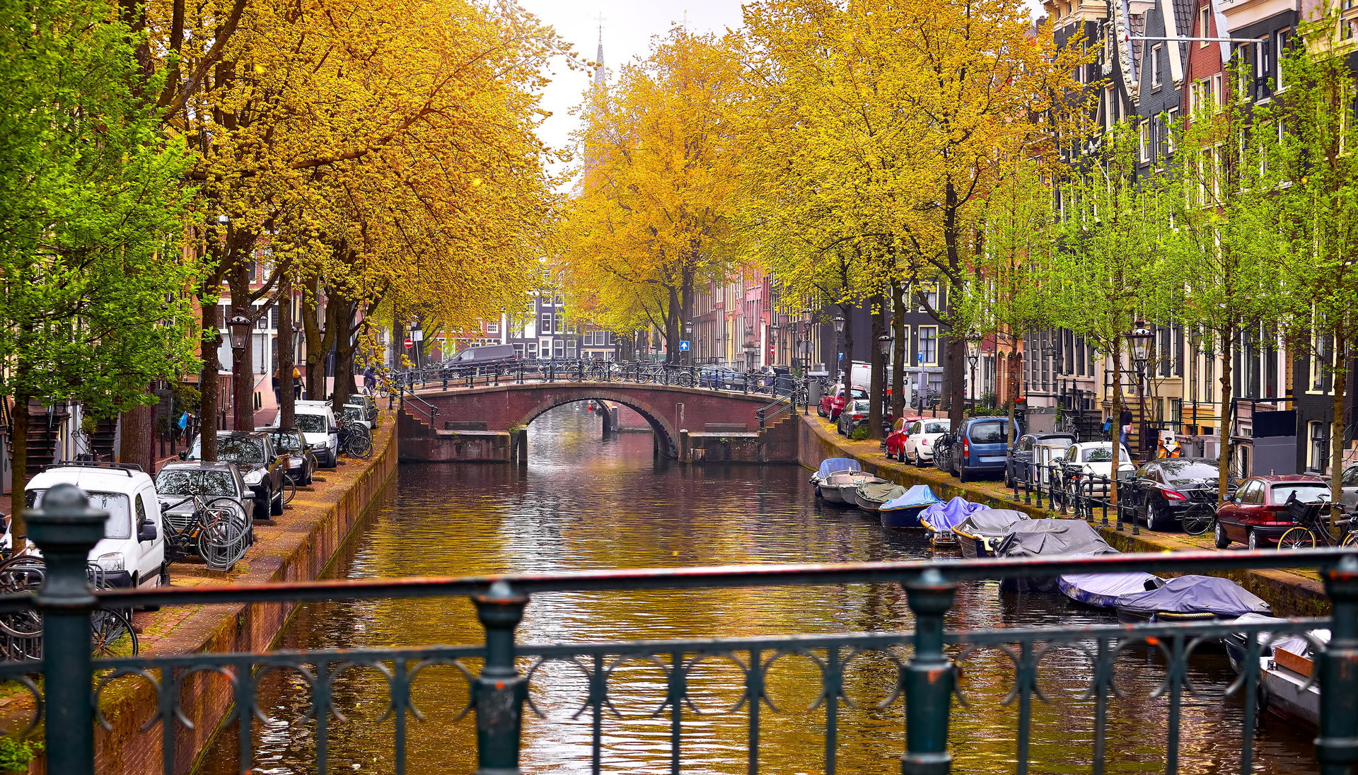 Netherlands Amsterdam river Amstel with traditional houses at bank and boats at water canal