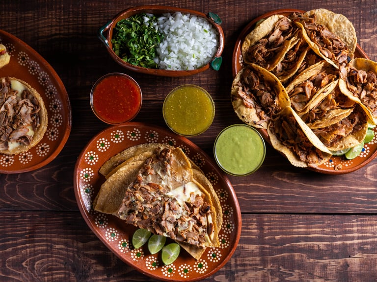 A variety of Mexican street tacos served with salsa and garnishes on a rustic wooden table.