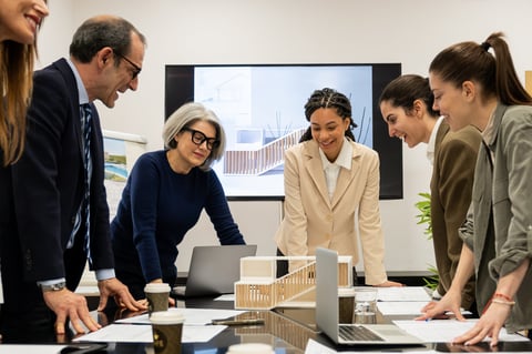 Profesionales de negocios discutiendo modelo arquitectónico y planos durante reunión de equipo