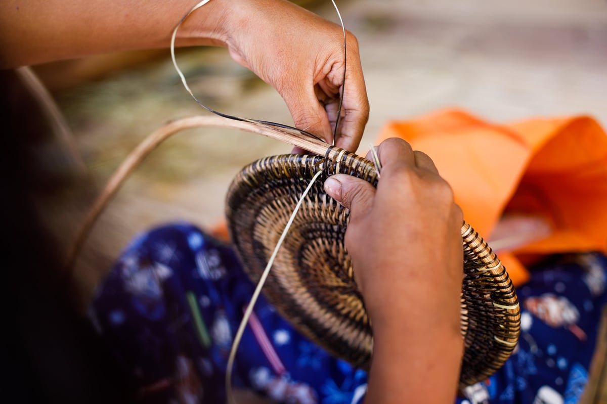 Artesana tejiendo cestería tradicional con fibras naturales en taller artesanal