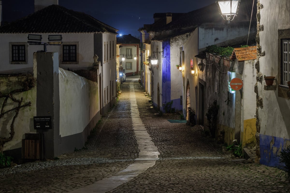 Calle colonial empedrada de noche con luces cálidas