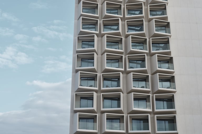 Fachada de edificio contemporáneo con balcones geométricos contra cielo azul