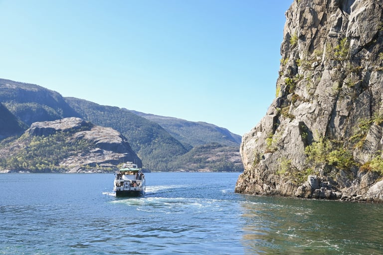 Sightseeing catamaran ship cruising with passengers in scenic fjord surrounded by mountains
