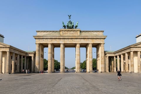 Brandenburg Gate in Berlin with classical columns, quadriga sculpture on top, and empty plaza under clear blue sky