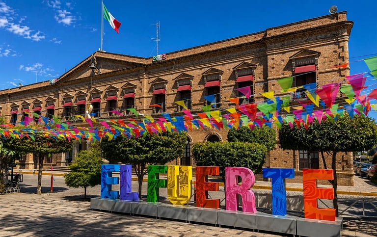 Historic yellow stone building with Mexican flag and colorful WELCOME sign in El Fuerte