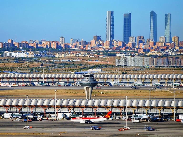 Aerial view of an airport runway with the city skyline featuring tall office buildings in the background under clear blue sky