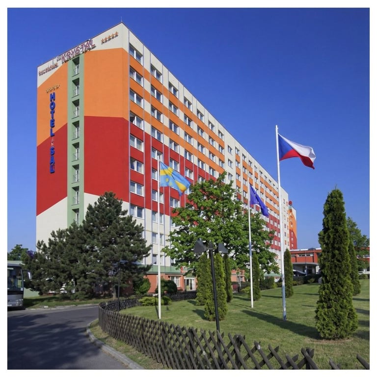 Colorful residential apartment building with orange and red facade, Polish flag, green landscaping, and clear blue sky