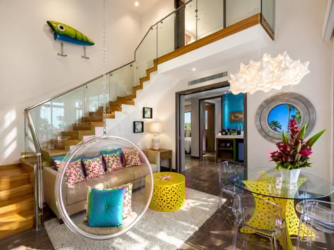 Sala moderna con escalera de madera, silla colgante circular, lámpara de papel y decoración colorida