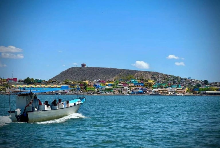 Fishing boat on turquoise water with colorful hillside village and clear blue sky in background
