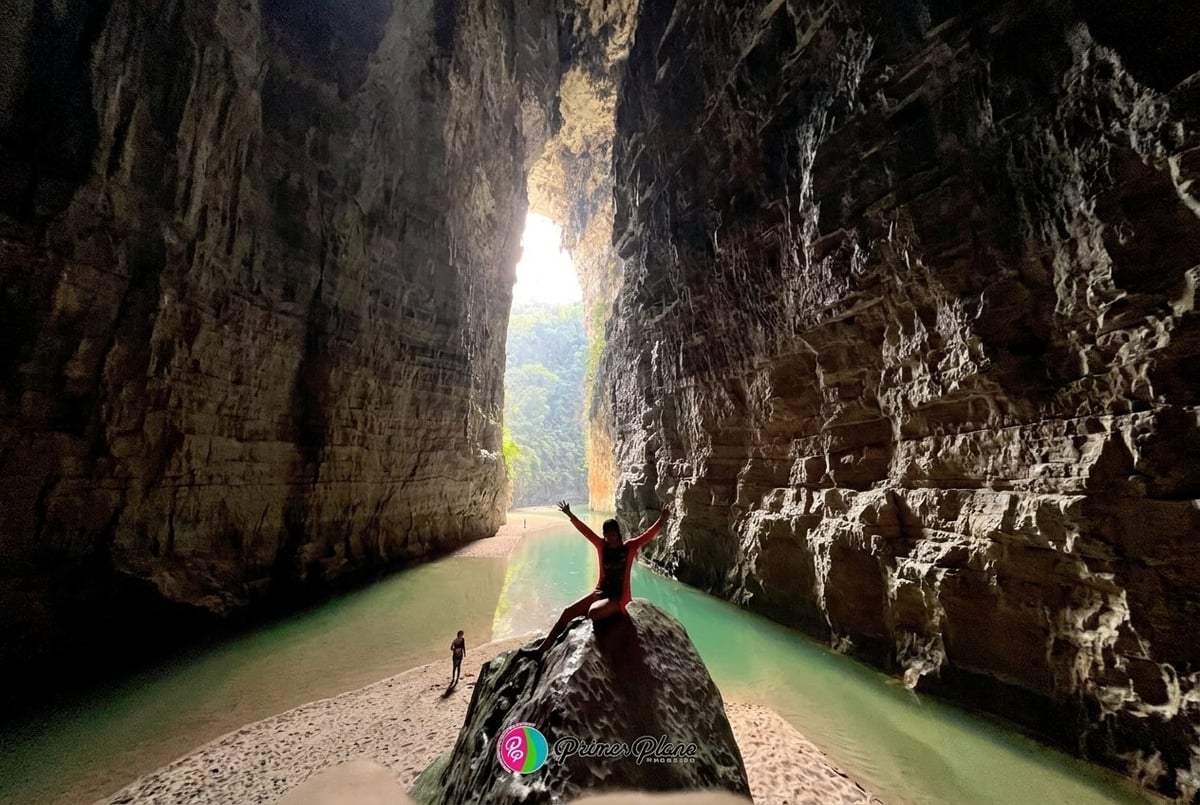 Person kayaking through a narrow canyon with towering rock walls and turquoise water leading toward bright daylight