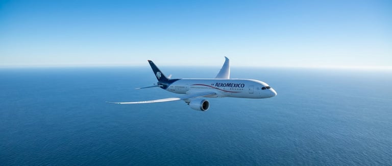 Bombardier aircraft flying over blue ocean water under clear sky