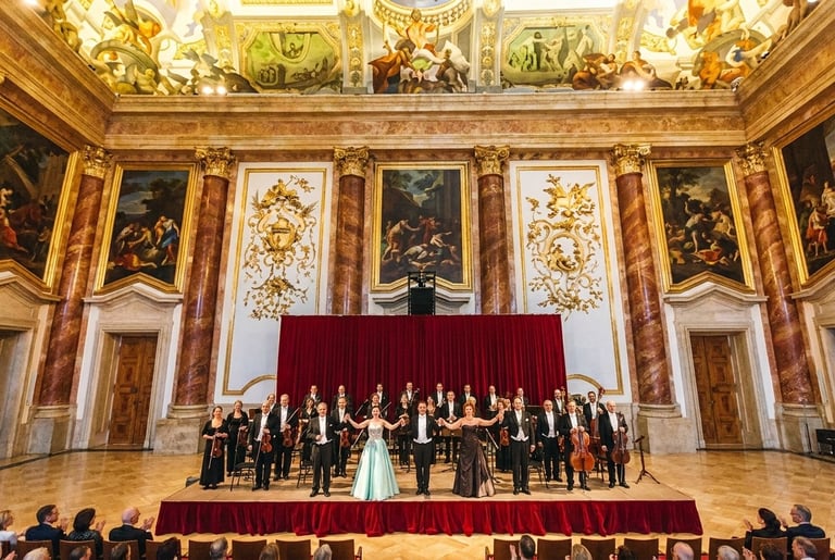 Choir performance in ornate baroque hall with gold decorative walls, red velvet curtain, and classical paintings on ceiling
