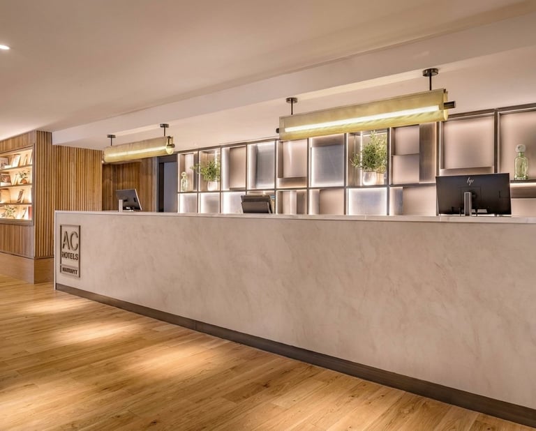 Modern office reception desk with white storage cubbies, warm lighting, and wooden flooring in a contemporary lobby space