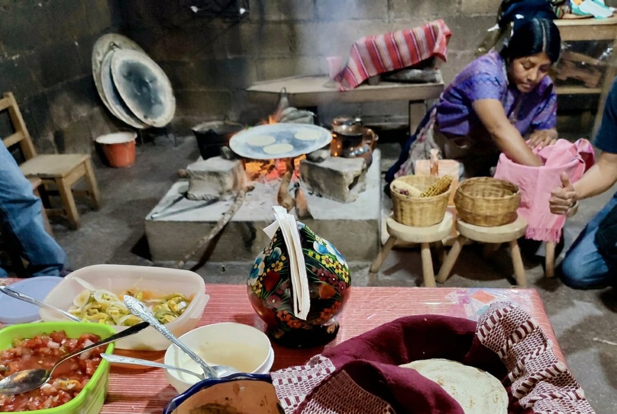 Traditional Asian kitchen with family preparing food, featuring a central cooking area and workers handling bamboo containers and dishes.