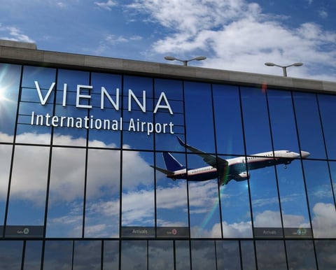 Vienna International Airport terminal facade with glass windows reflecting a plane and blue sky
