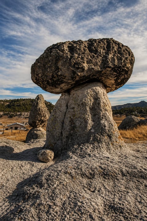 Large balanced rock formation perched on top in desert landscape
