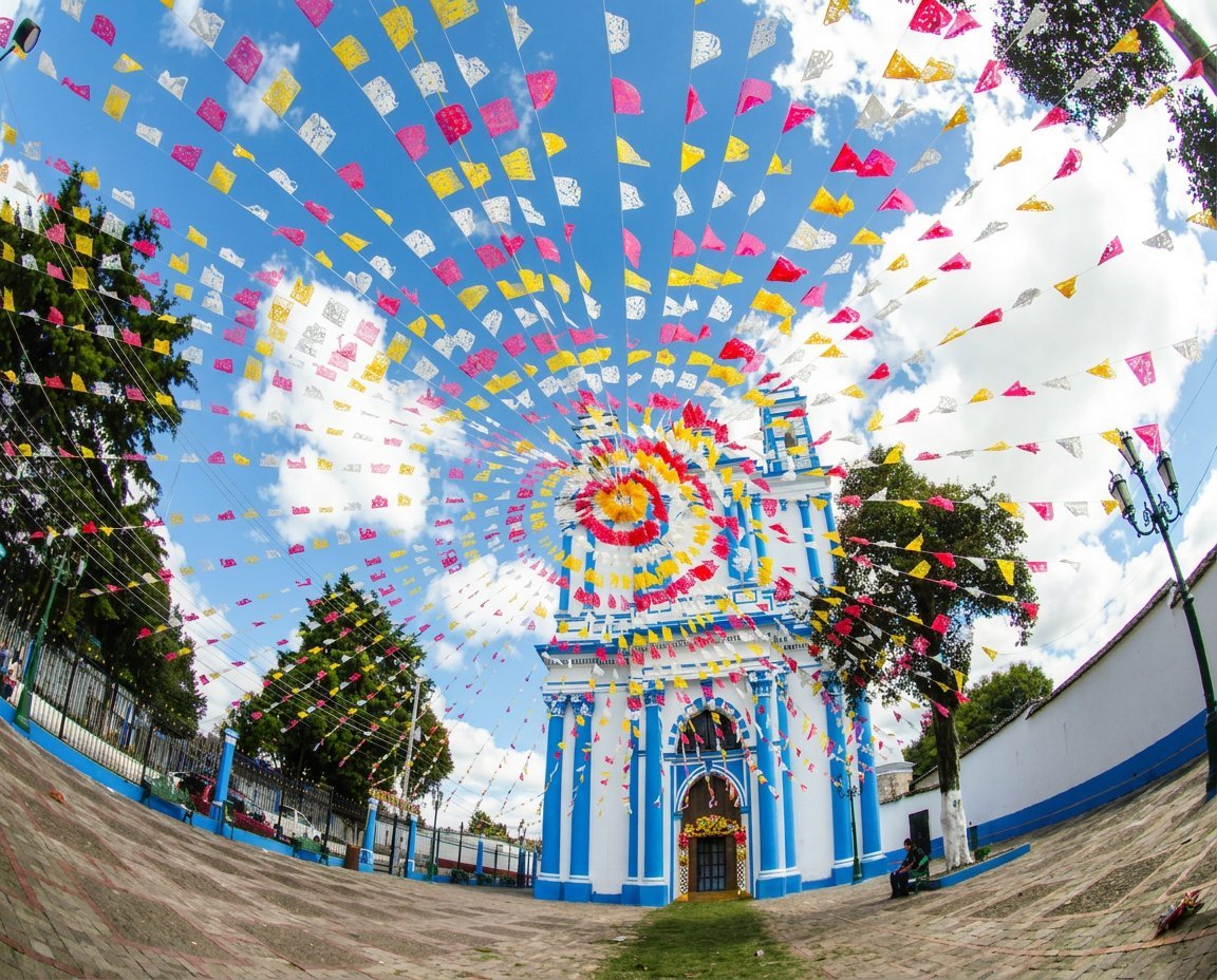 Blue and white church with spiral pattern of colorful kites flying overhead in sky