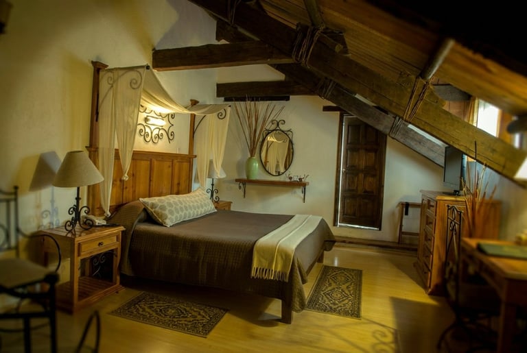 Rustic bedroom with wooden furniture, exposed beams, and warm lighting featuring a bed with yellow bedding and decorative accessories
