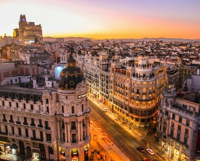 Aerial sunset view of Madrid cityscape with illuminated historic buildings and cathedral in the distance